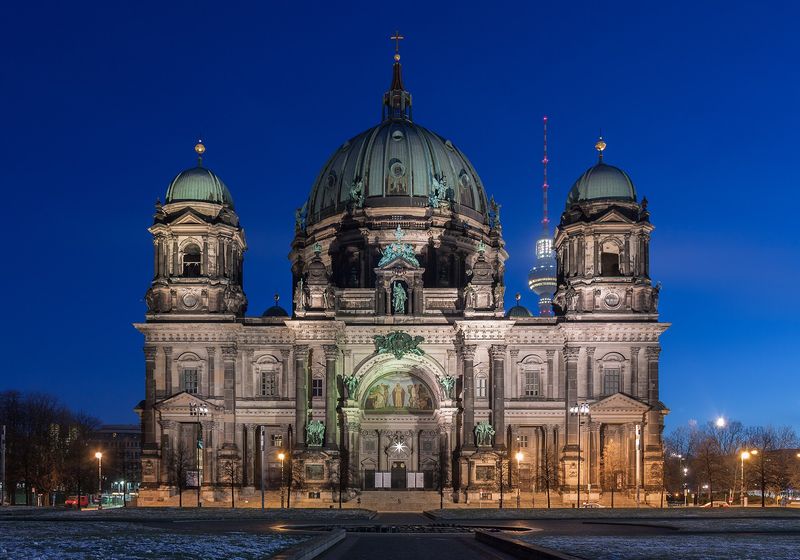 Die Westfassade des Berliner Doms mit ihren grünen Kuppeln in der blauen Stunde, rechts dahinter der Fernsehturm